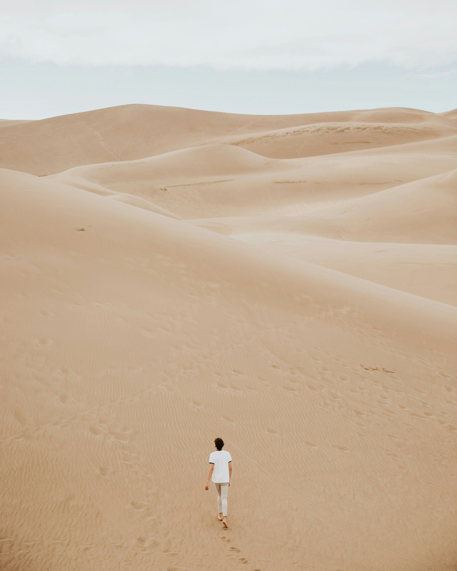 person walking on sand dune